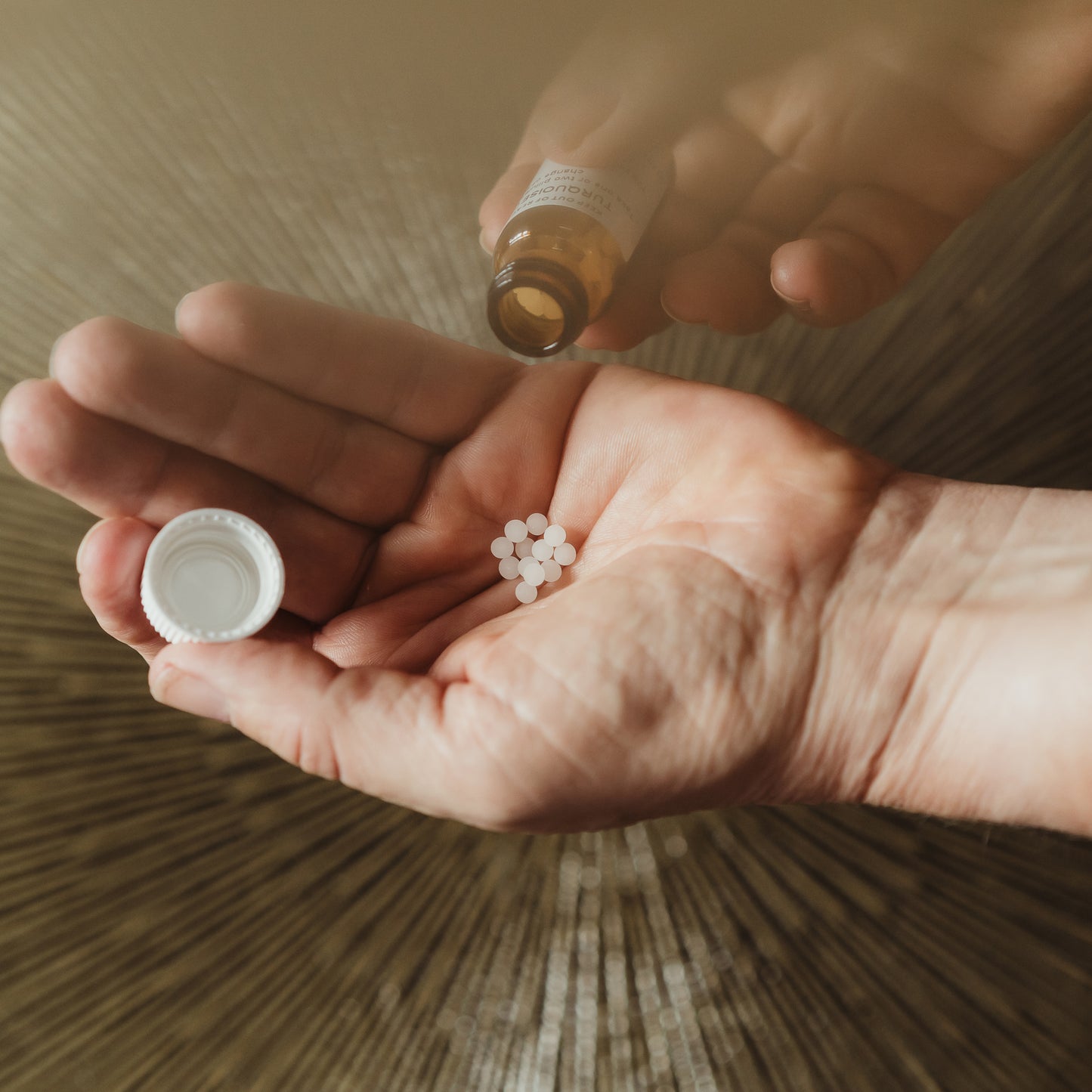 A person's hands holding a homeopathic remedy with pellets and a bottle.